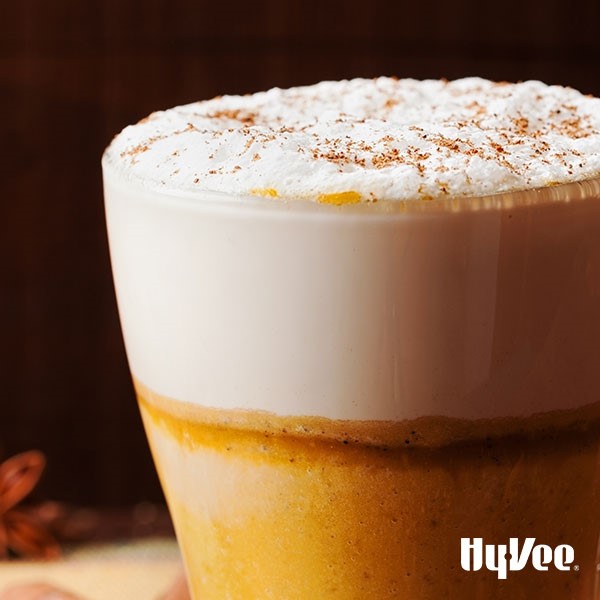 Orange and white drink topped with whipped cream and spices
