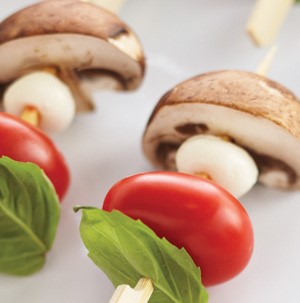 Basil leaf, cherry tomato, mozzarella ball and mushroom on wooden skewers