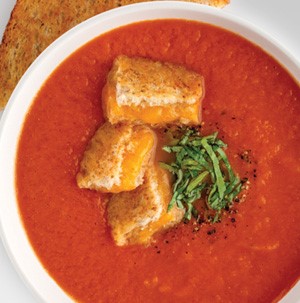 Tomato-basil soup with cheesy croutons, sliced basil, and freshly ground black pepper