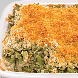 White casserole dish filled with creamy green beans and a crumbled bread crumb topping