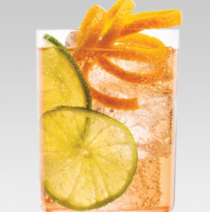 Glass filled with ice, rum punch, lime slices, and orange peel