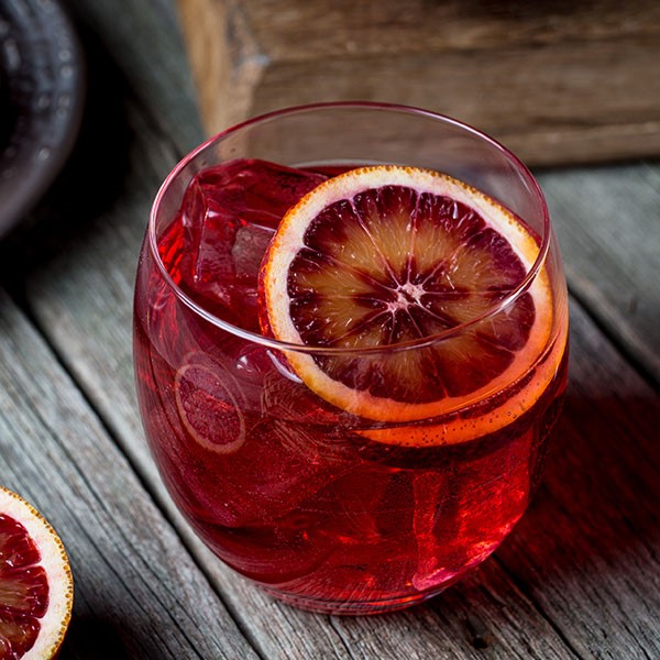 Glass of sparkling blood orange cocktail and garnished with a blood orange slice