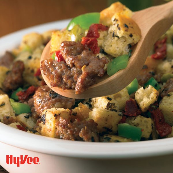 Stuffing pictured in a bowl with bread cubes,, sausage, and diced peppers