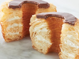 Croissant dough shaped into donuts, split open with chocolate glaze on top