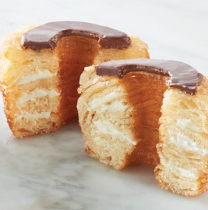 Croissant dough shaped into donuts, split open with chocolate glaze on top