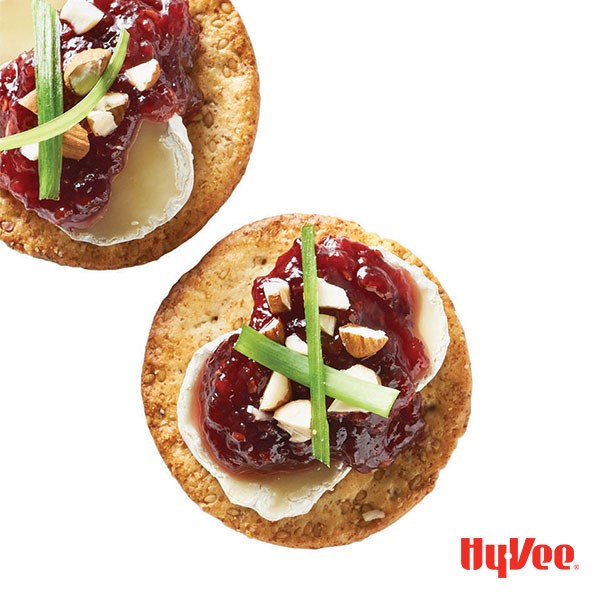 Round crackers topped with brie, hot pepper raspberry spread, chopped almonds and chives