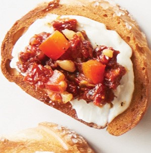 Pretzel bread covered in a layer of cream cheese and topped with sundried tomatoes