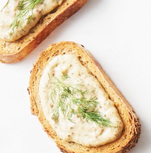 Artisan bread topped with mustard dill dip and garnished with fresh dill