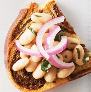 Slice of marbled rye topped with cannellini beans, onion and rosemary