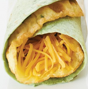 Spinach tortilla wrapped around omelet filled with shredded cheese