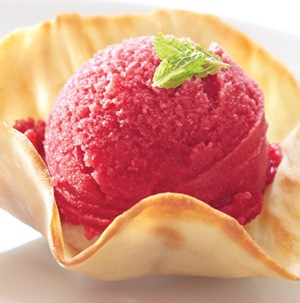 Red sorbet in a waffle cone cup topped with mint leaves