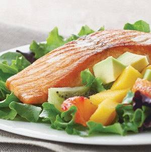 Salmon and avocado and mango salad served atop a bed of lettuce