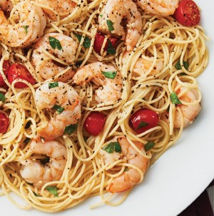Pasta topped with shrimp, cherry tomatoes, parsley, and freshly cracked black pepper
