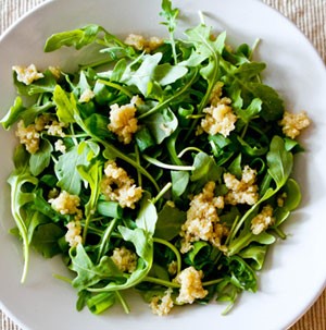 Arugula in a bowl topped with cooked quinoa