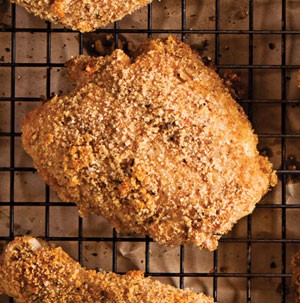 Breaded chicken on a wire rack over parchment paper