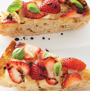 Toasted ciabatta bread slices topped with brie, strawberry slices, balsamic and basil