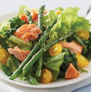 Mixed green salad topped with flaked cooked salmon, halved cherry tomatoes, and asparagus spears