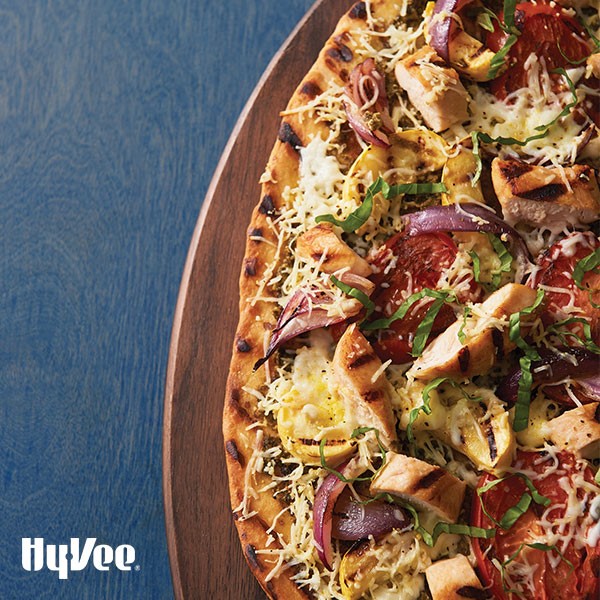 Grilled flat bread topped with sliced red onions, grilled chicken, grilled zucchini and blistered tomatoes