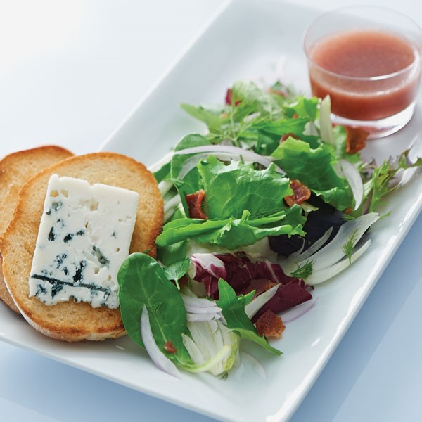 Plate of fennel salad served with a side of vinaigrette and two bread slices topped with cheese