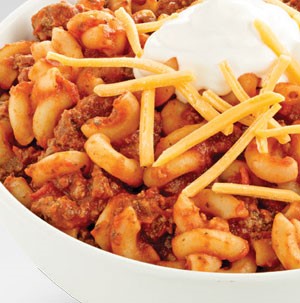 Elbow macaroni with red meat sauce topped with shredded cheese and sour cream