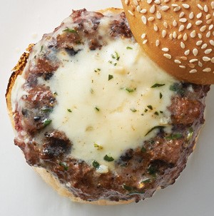 Burger patty topped with melted tarragon butter on a sesame bun