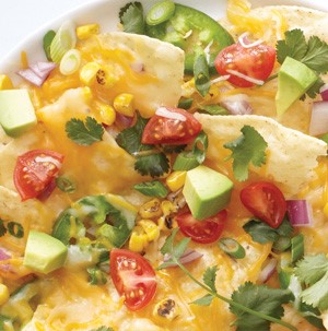 Tortilla chips topped with melted cheese, sliced jalapeno, quartered cherry tomatoes, and cubed avocado