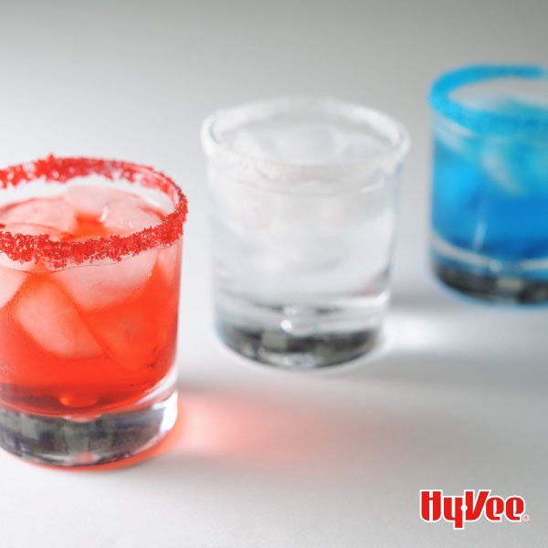 Three sugar-rimmed glasses filled with red, white and blue liquid