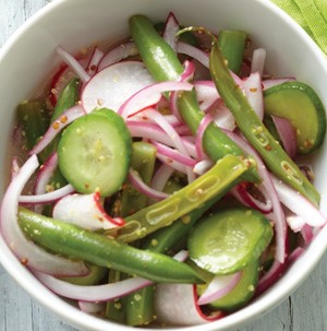Sliced cucumbers and red onions with green beans and spices in a bowl