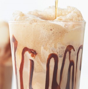 Glass drizzled with chocolate and filled with foamy beverage
