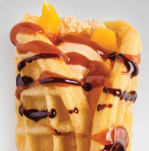 Waffle wrapping mango strips and ice cream and drizzled with caramel and chocolate sauce