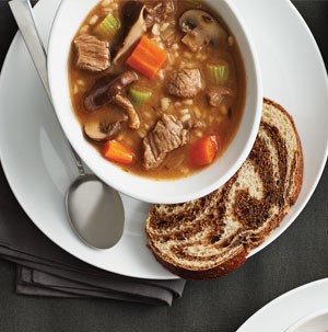 Bowl of beef and barley with mushrooms served with a slice of bread