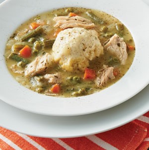 White bowl filled with dumplings and shredded turkey with mixed vegetables