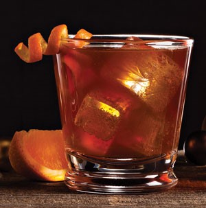 Glass filled with ice cubes, maple ale, spice, and garnished with an orange peel