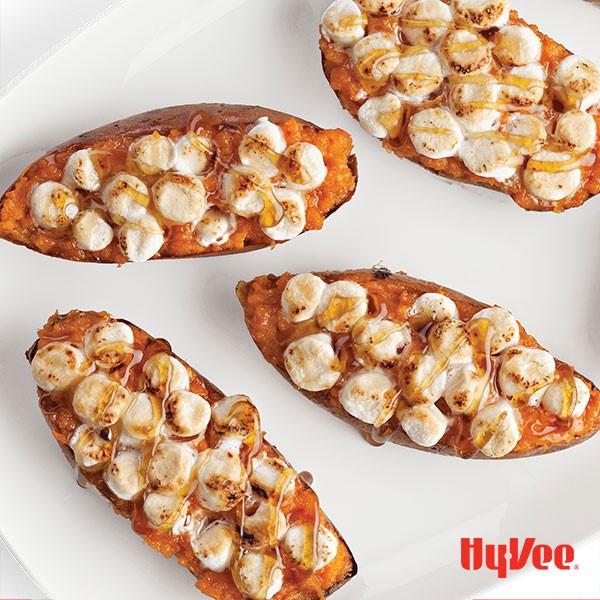 Stuffed sweet potatoes topped with browned mini marshmallows and drizzled maple syrup