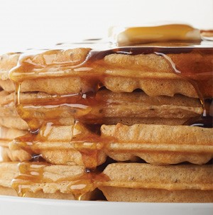 Stacked waffles topped with maple syrup and a butter patty