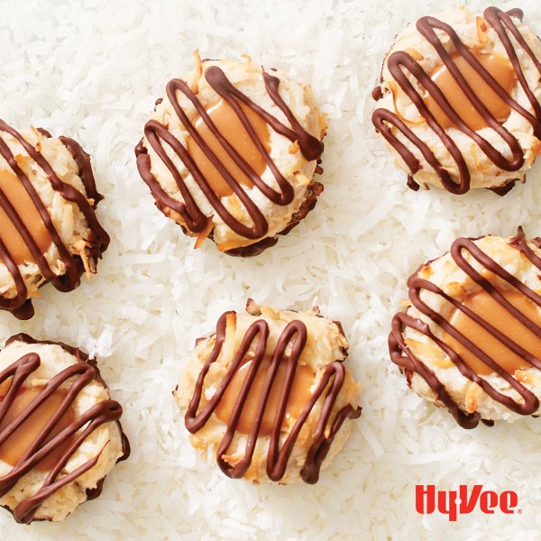 Carmel coconut thumbprints topped with drizzled melted chocolate on a bed of flaked coconut