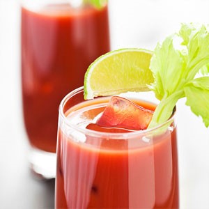 Glass filled with bloody mary mocktail and ice, garnished with a lime wedge and celery stalk