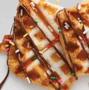 Angel food cake shaped into a waffle, drizzled with hazelnut spread and colored sprinkles
