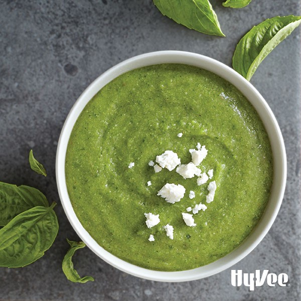 Bowl of creamy broccoli-basil soup topped with crumbled cheese