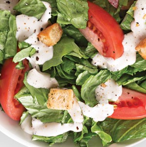Bowl of salad topped with buttermilk ranch, tomatoes and croutons