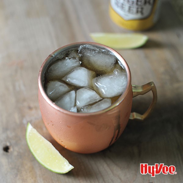 Copper cup filled with mule, ice cubes and lime wedges on the side