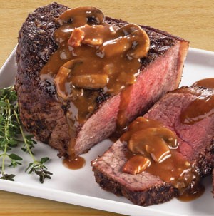 Beef bottom round roast topped with beer and mushroom sauce on a white platter