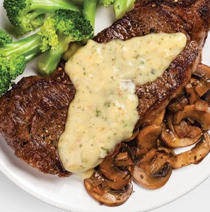 Grilled steak stuffed with sliced mushrooms, with sauce on a white plate with a side of broccoli