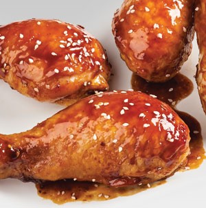 Chicken legs coated in sauce and sprinkled with sesame seed