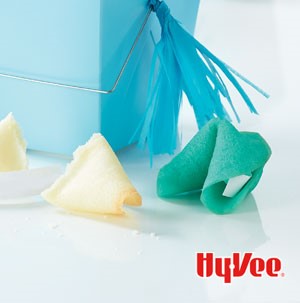 Green and white fortune cookies next to a blue gift box