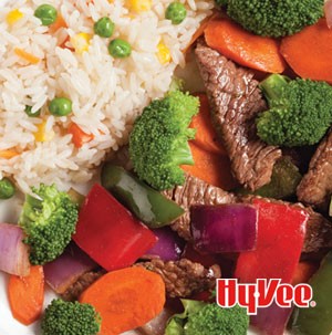 Beef strips with broccoli florets, carrot slices, chopped bell peppers, and red onions next to fried rice.