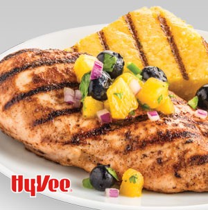 Plate of grilled chicken breast topped with peach blueberry salsa and grilled polenta