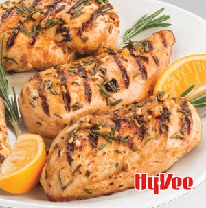Grilled chicken with lemon wedges and fresh rosemary sprigs