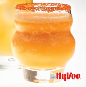 Orange fizzy drink in glass rimmed with orange sprinkles