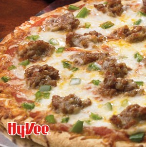 Pizza garnished with large chunks of sausage and diced green peppers